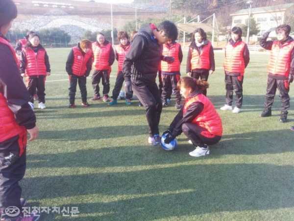▲ 농다리여자FC 코치가 진천역사테마공원 축구장에서 팀원들이 지켜보는 가운데 드리볼 돌파를 시도하는 시범을 보이고 있다.