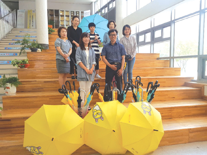 이혜숙(사진 뒷줄 오른쪽 첫번째) 동성초등학교 교장과 이하민(사진뒷줄 가운데) 학생회장이 학교운영위원들과 함께 ‘깜빡 우산’을 펼치고 포즈를 취하고 있다.