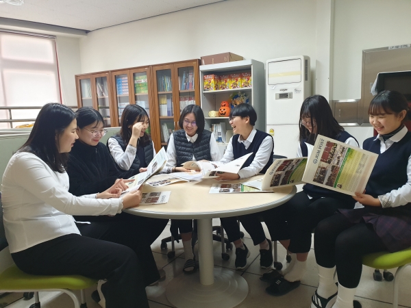 진천여중 영자신문반 동아리 학생들이 첫 발행된 영자신문 'JGM POST'를 보고있다.
